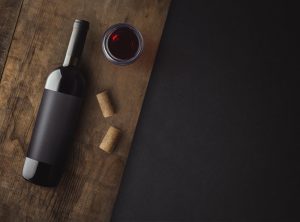 Flaska rött vin med etikett på gammal kartong.